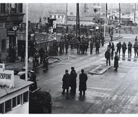 4. Dezember 1961 - Unter den Augen ostdeutscher Soldaten und Polizisten installieren Bauarbeiter auf der Ostseite des Checkpoint Charlie eine Panzersperre.