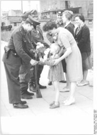 Die Berliner Bevölkerung fühlt sich mit den bewaffneten Kräften eng verbunden, die zur Sicherung des Friedens in der Hauptstadt der DDR ihren Dienst tun. Am Kontrollpunkt Heinrich-Heine-Straße werden am 15.8.1961 Blumen und kleine Geschenke übergeben.