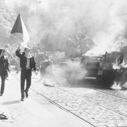 Einwohner von Prag mit tschechoslowakischer Flagge vor einem brennenden sowjetischen Panzer 1968